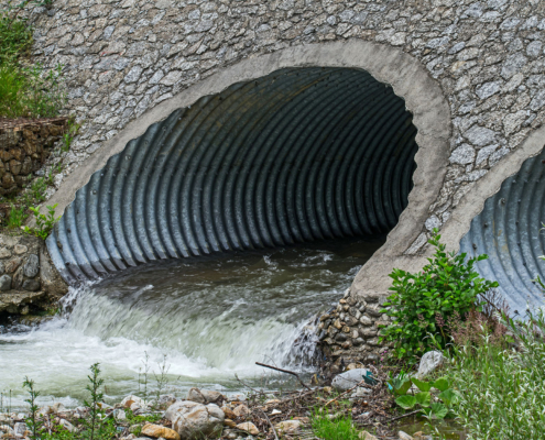 Water drains through pipes, under a bridge