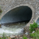 Water drains through pipes, under a bridge